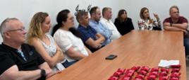 Grupa uczestników szkolenia siedzi przy długim drewnianym stole konferencyjnym.