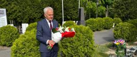 mężczyzna w garniturze składa kwiaty na cmentarzu
