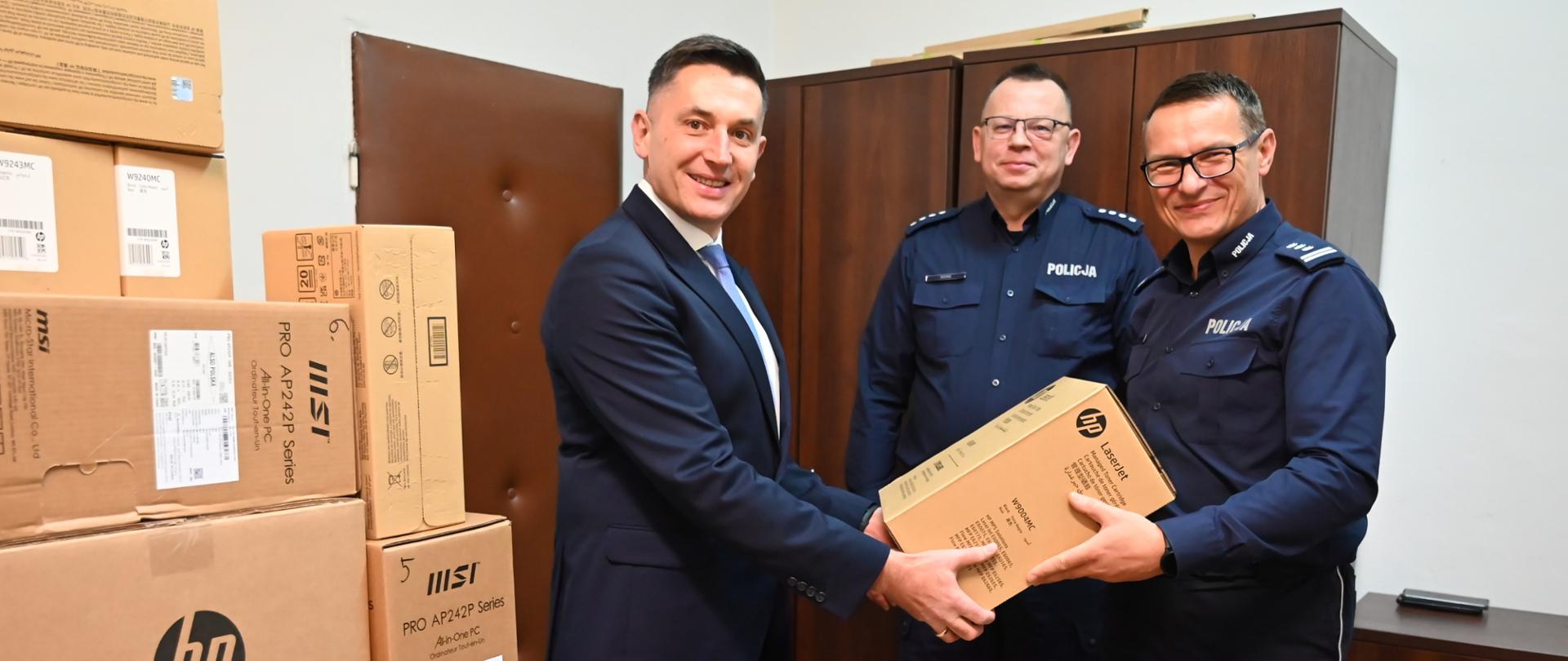 Burmistrz przekazuje komendantowi karton ze sprzętem komputerowym