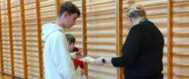 Pani wicedyrektor wręcza uczniom, którzy uzyskali wyróżnienia w konkursie, dyplomy i nagrody, w tle drabinki gimnastyczne