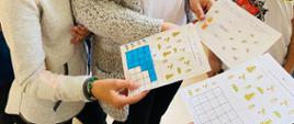 Dziewczynki pokazują łamigłówki obrazkowe związane tematycznie z pszczołami