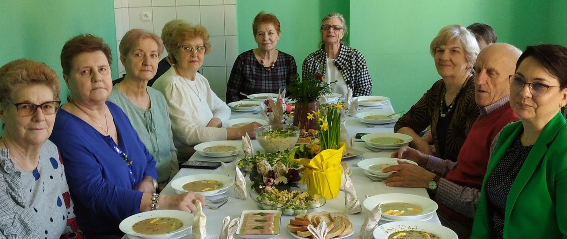 Członkowie Klubu Senior+ wraz z kierownikiem mops przy wielkanocnym stole