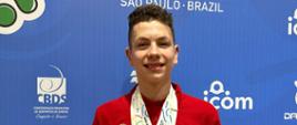 Rafał Wójcik na tle ścianki Młodzieżowych Igrzyskach Olimpijskich Niesłyszących ze zdobytymi złotymi medalami zawieszonymi na szyi