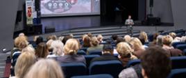 Uczestnicy konferencji w Centrum Kultury i Wypoczynku w Proszowicach podczas spotkania, na scenie jeden z prelegentów