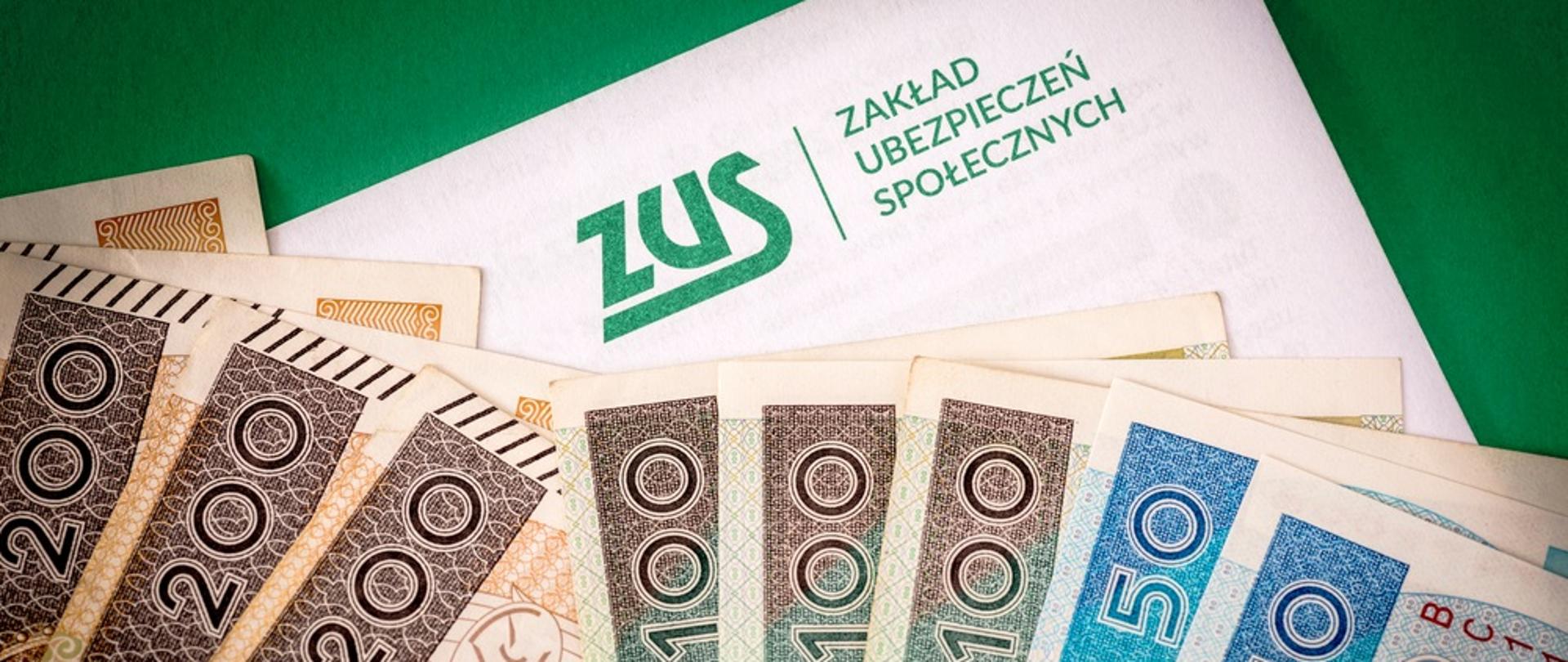 Zdjęcie przedstawia plik banknotów polskich złotych 50, 100, 200 na tle kartki z podpisem ZUS - Zakład Ubezpieczeń Społecznych 