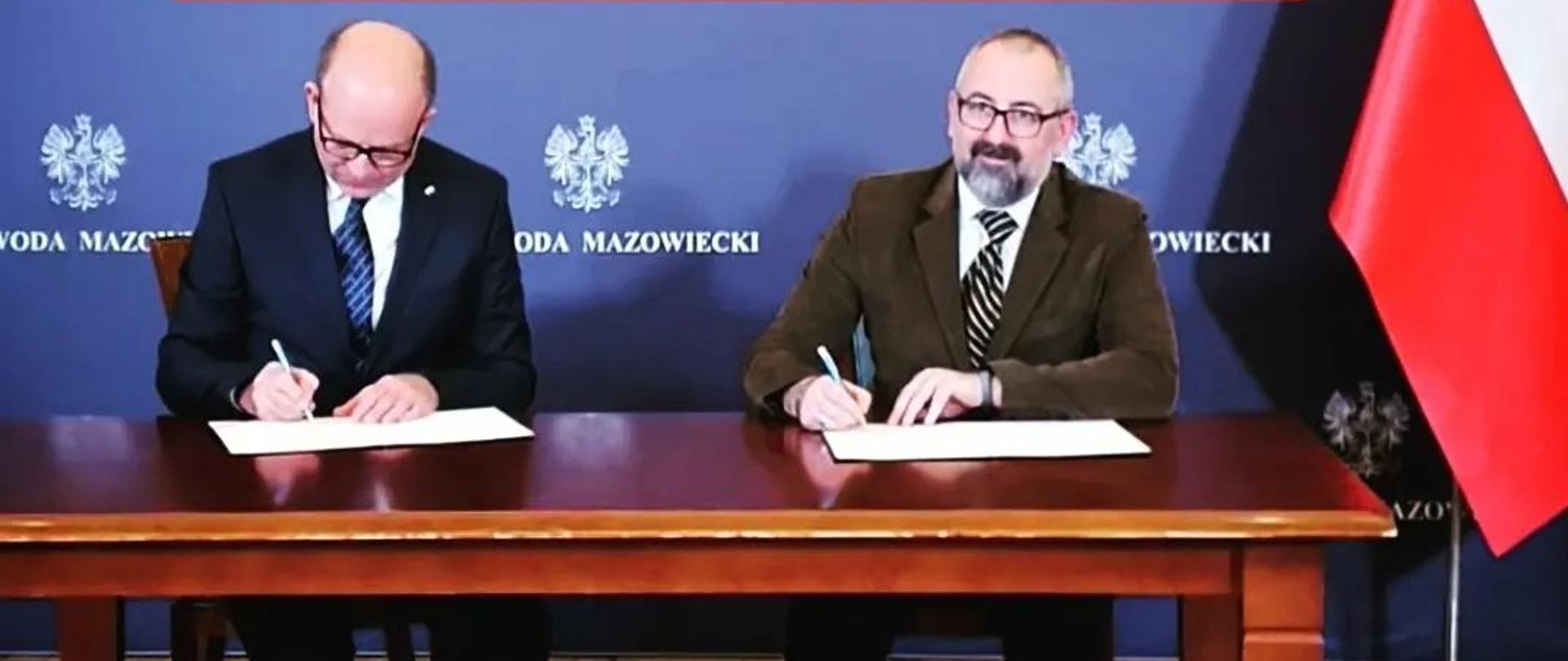 Zdjęcie przedstawia Wojewodę Mazowieckiego Konstantego Radziwiłła oraz Starostę Przasnyskiego Krzysztofa Bieńkowskiego podczas podpisywania umowy na dofinansowanie budowy kompleksu basenów otwartych w Przasnyszu.