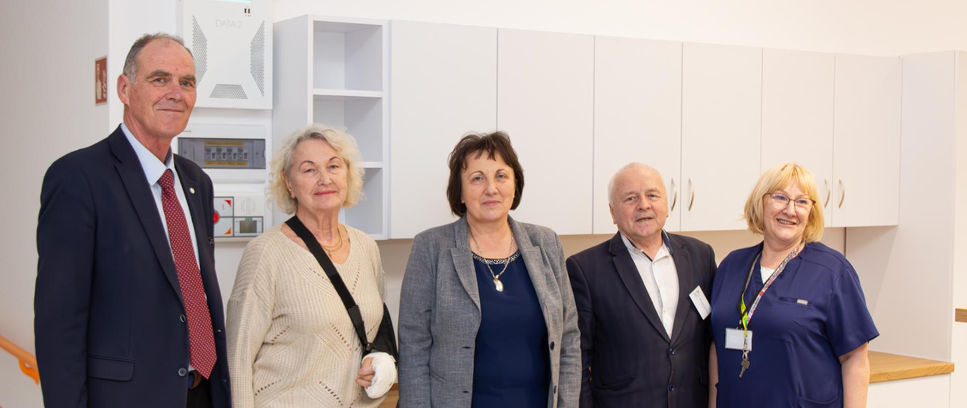 Widok na jeden z punktów pielęgniarskich. W tle ciąg szafek ściennych i podłogowych z szufladami. Na ich te personel, dyrekcja szpitala oraz starosta i wicestarosta Ryszard Domański.