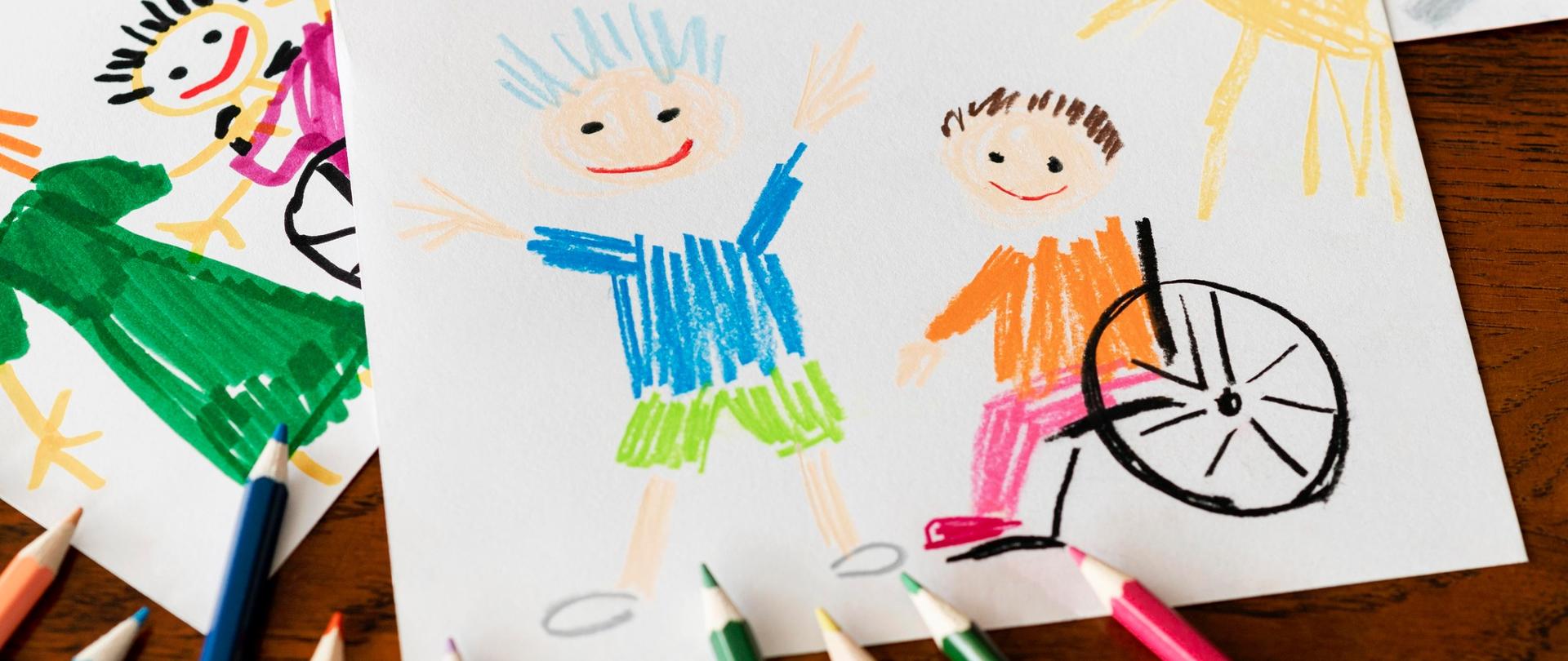 Dziecięcy rysunek przedstawiający dwójkę dzieci, w tym jedno na wózku inwalidzkim. Kolorowe kredki.