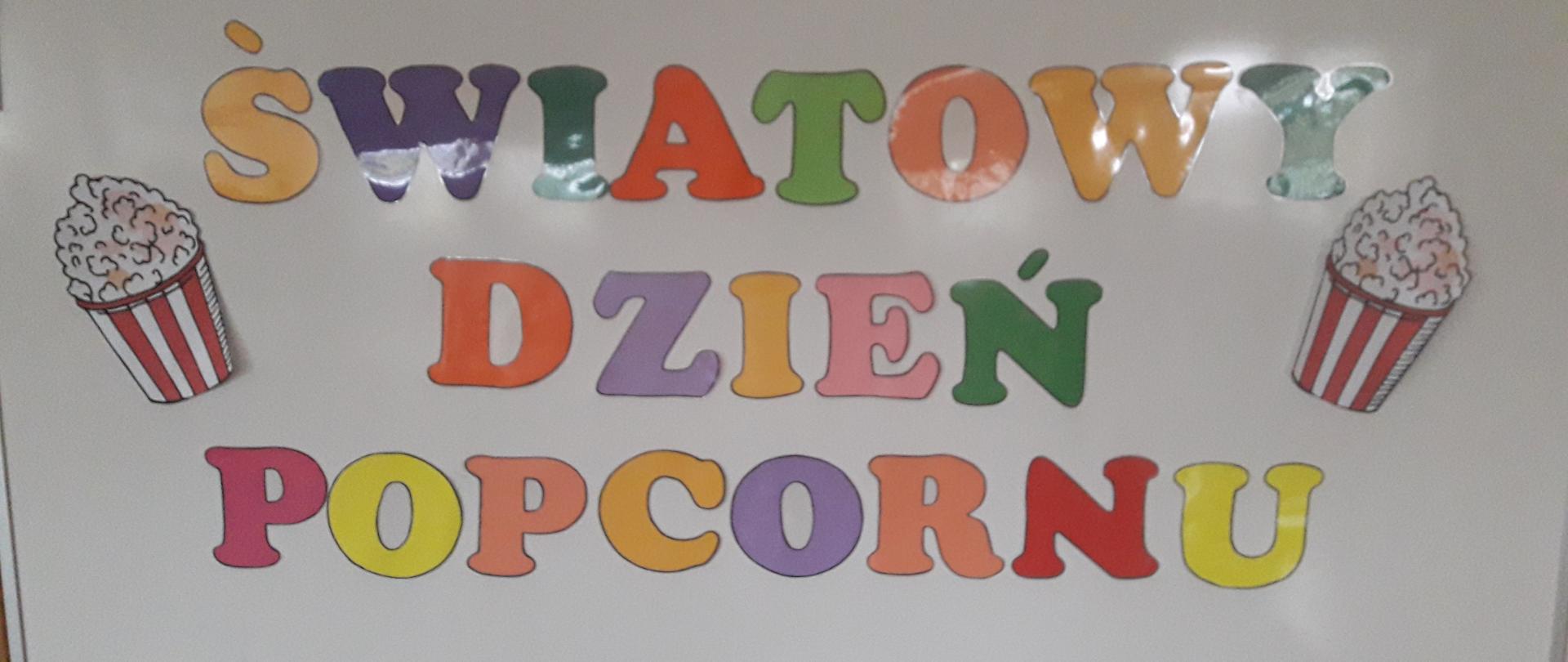 Kolorowy napis „Światowy Dzień Popcornu” umieszczony na tablicy.