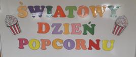 Kolorowy napis „Światowy Dzień Popcornu” umieszczony na tablicy.