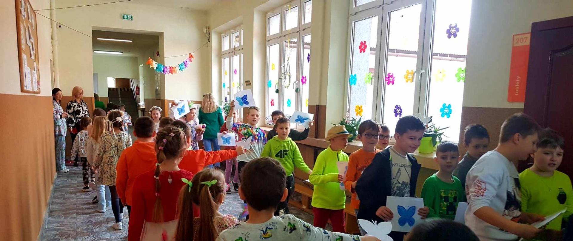 Uczniowie biorą udział w wiosennym pochodzie.