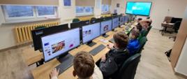 Wnętrze sali informatycznej, chłopcy przy komputerach podczas tworzenia prezentacji.