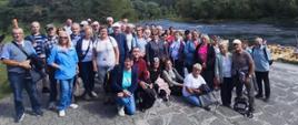 Grupa dorosłych osób pozuje do zdjęcia przy rzece