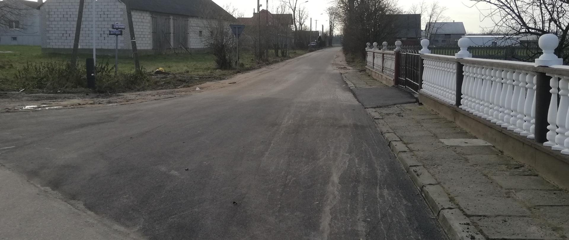Zdjęcie przedstawia wyremontowaną ulicę Marii Konopnickiej w Gminie Lutocin. Po jej obu stronach znajdują się prywatne działki. 