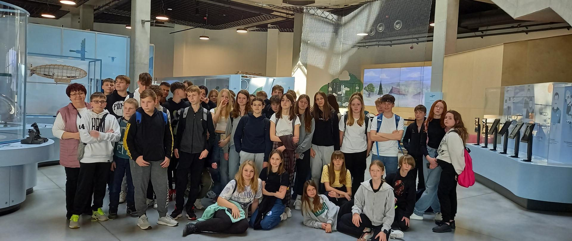 Wszyscy uczestnicy wycieczki z klas 6,7, 8a i 8b do Podkarpackiego Centrum Nauki- Łukasiewicz na tle wystawy o lotnictwie.