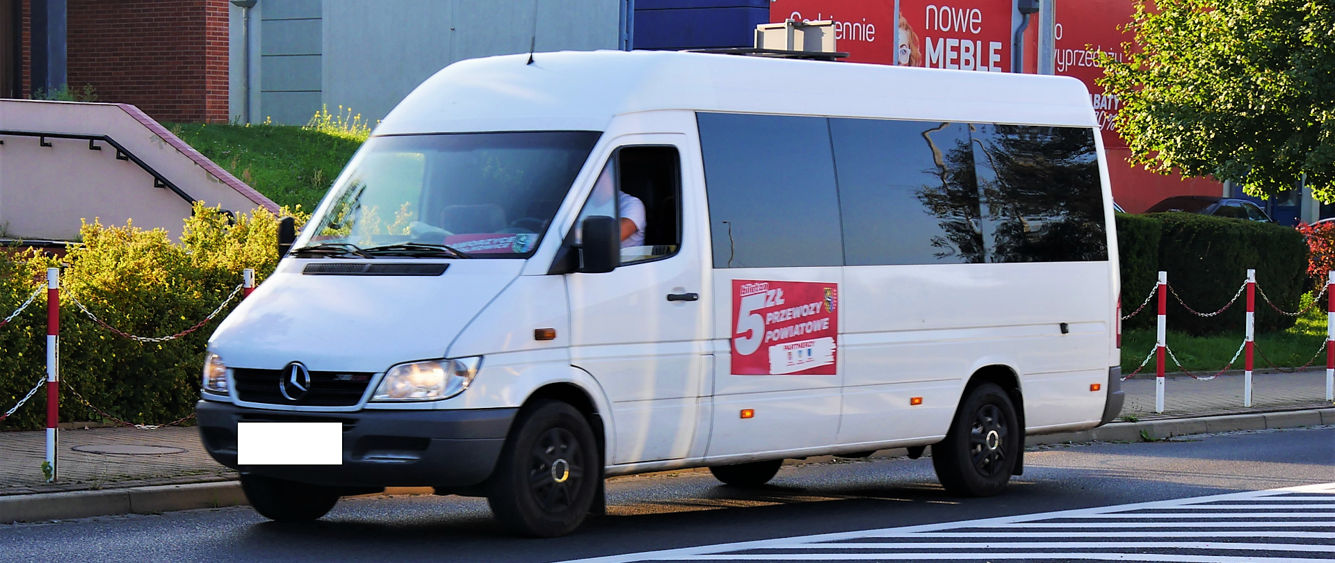 biały bus jedzie ulicą