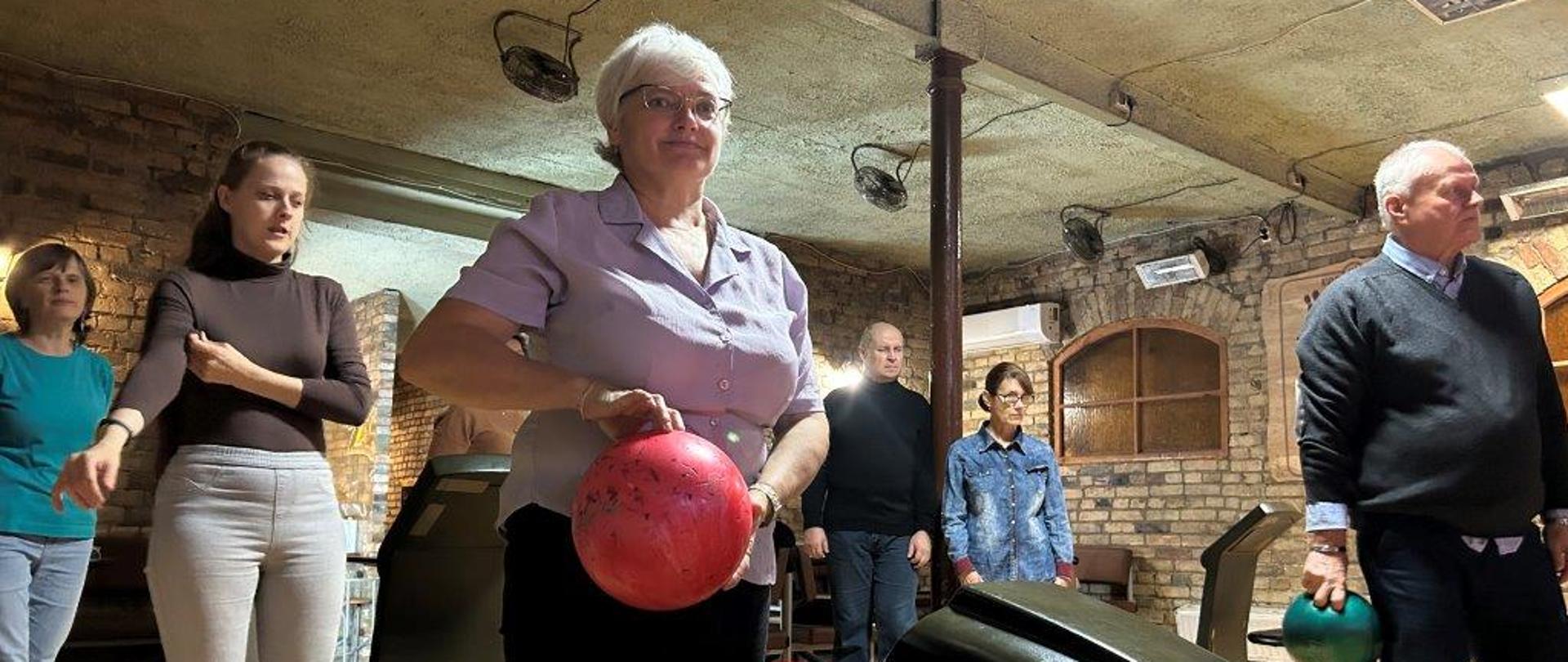 Uczestnicy z kulami w ręku stoją przy bieżni