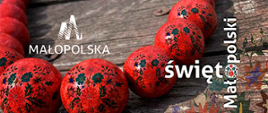 zdjęcie przedstawia na drewnianym tle czerwone korale z kwiatowym wzorem, po prawej stronie napis Święto Małopolski