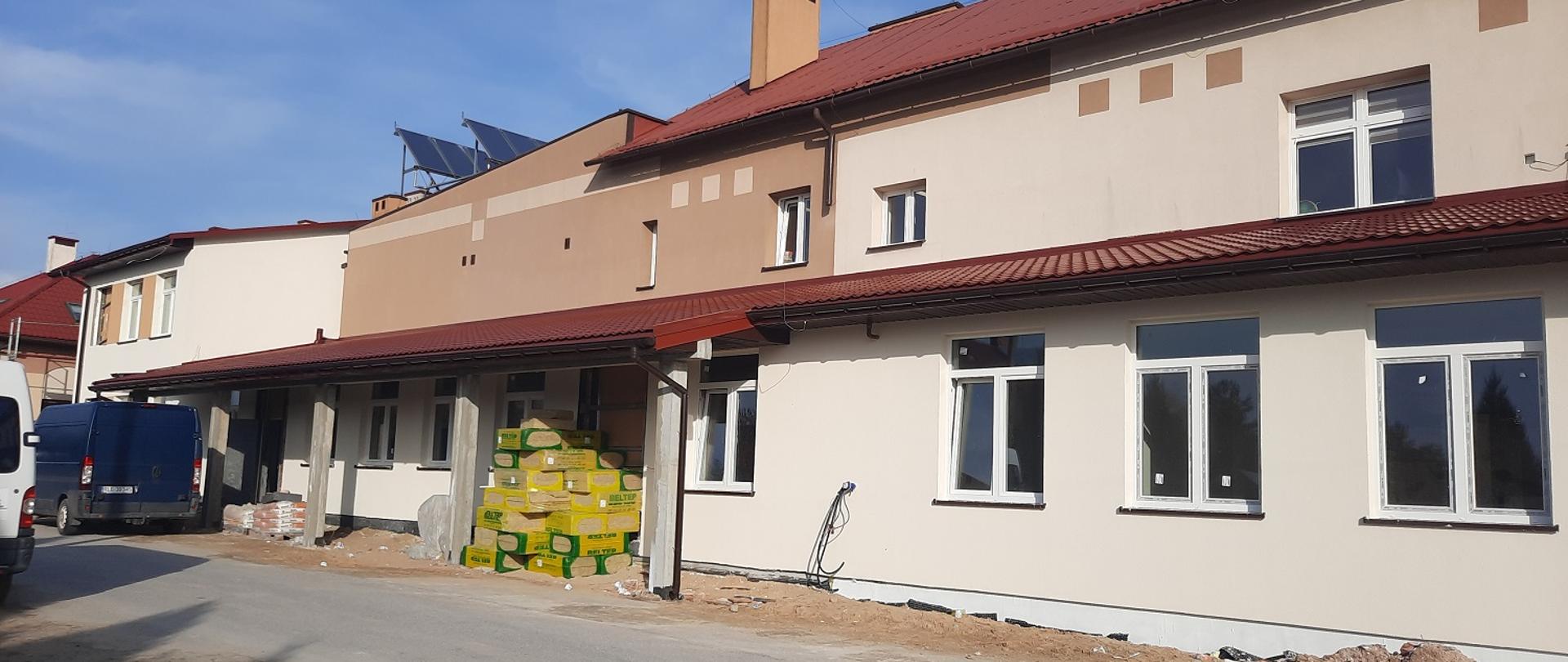 rozbudowa budynku, budynek jasno i ciemno brązowy z czerwonym dachem nowe wstawione okna 