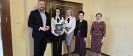 Mężczyzna i cztery kobiety pozują do zdjęcia na tle żółtej ściany