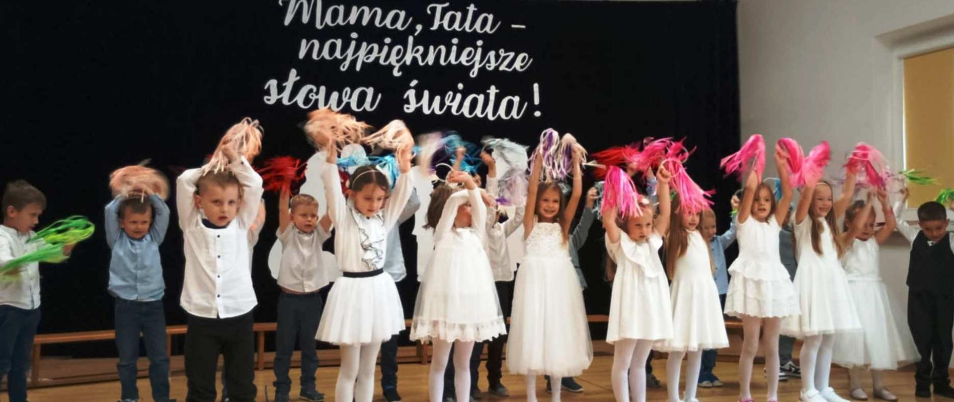 Dziewczynki i chłopcy z grupy 5-latków tańczą z pomponami.