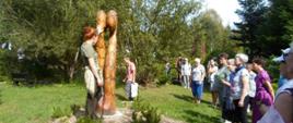 W herbarium - przewodnik stoi przy rzeźbie, obok uczestnicy wyjazdu