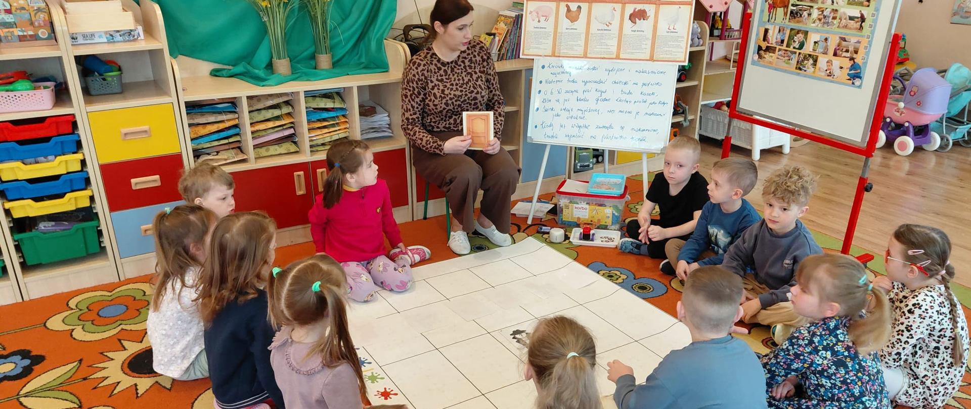 Dzieci siedzą i nauczyciel 