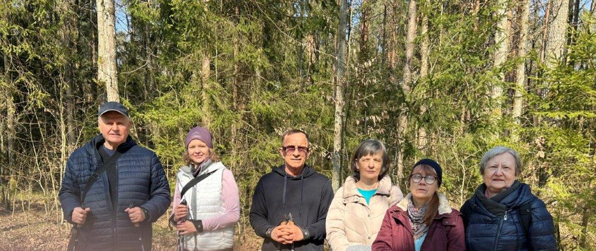 Uczestnicy z kijami nordic walking pozują do zdjęcia