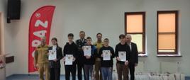 Fotografia grupowa wykonana w siedzibie PSP w Sokołowie Podlaskim, na zdjęciu nagrodzeni uczestnicy, trzymają w dłoniach dyplomy, oraz przedstawiciele Straży Pożarnej i Starostwa Powiatowego w Sokołowie Podlaskim.