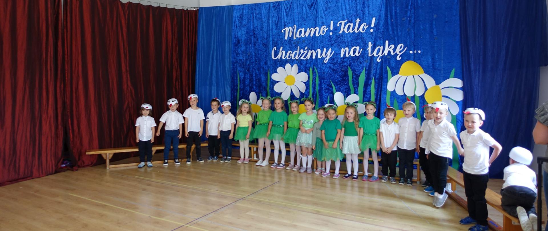Dzieci przebrane za żaby i bociany recytują wiersz.