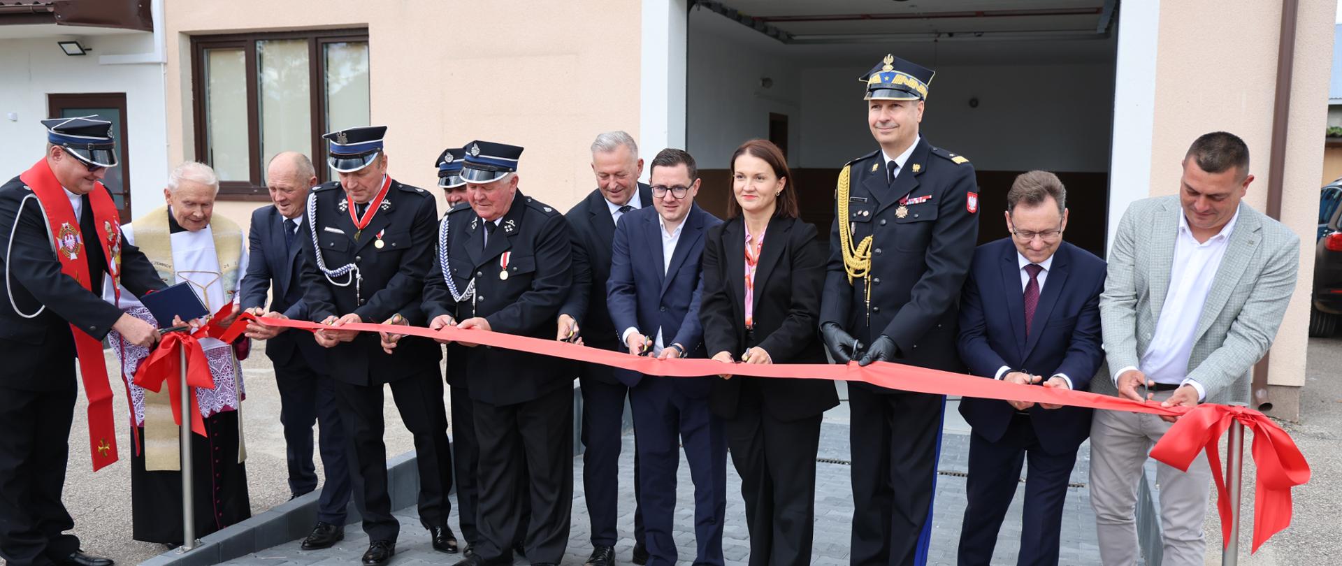 Wyznaczone osoby przecinają czerwoną wstęgę przed budynkiem OSP Bujały Mikosze.