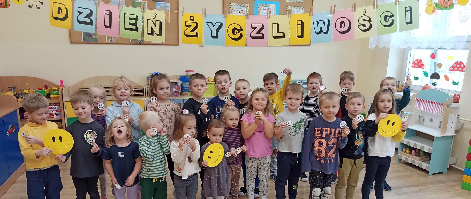 Wszystkie przedszkolaki pozują do zdjęcia pod napisem „Dzień życzliwości”. 