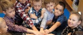 Uczniowie klasy pierwszej składają uroczyste przyrzeczenie dotyczące poszanowania książek trzymając dłonie na baśniach Andersena