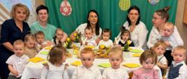 Na zdjęciu widać dzieci z grupy Słoneczka siedzące dookoła świątecznego stołu. Widać również Panią Dyrektor oraz ciocie.