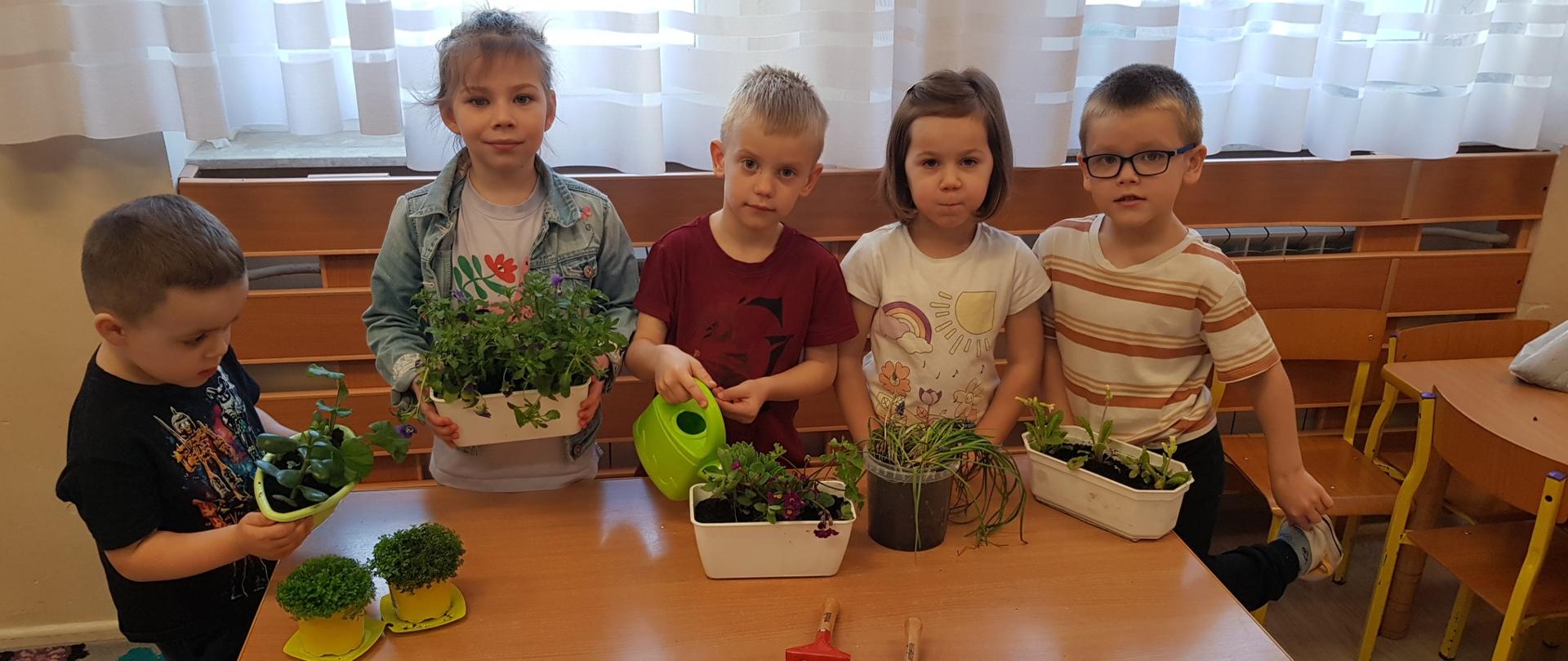 Dzieci przy stole z posadzonymi roślinami