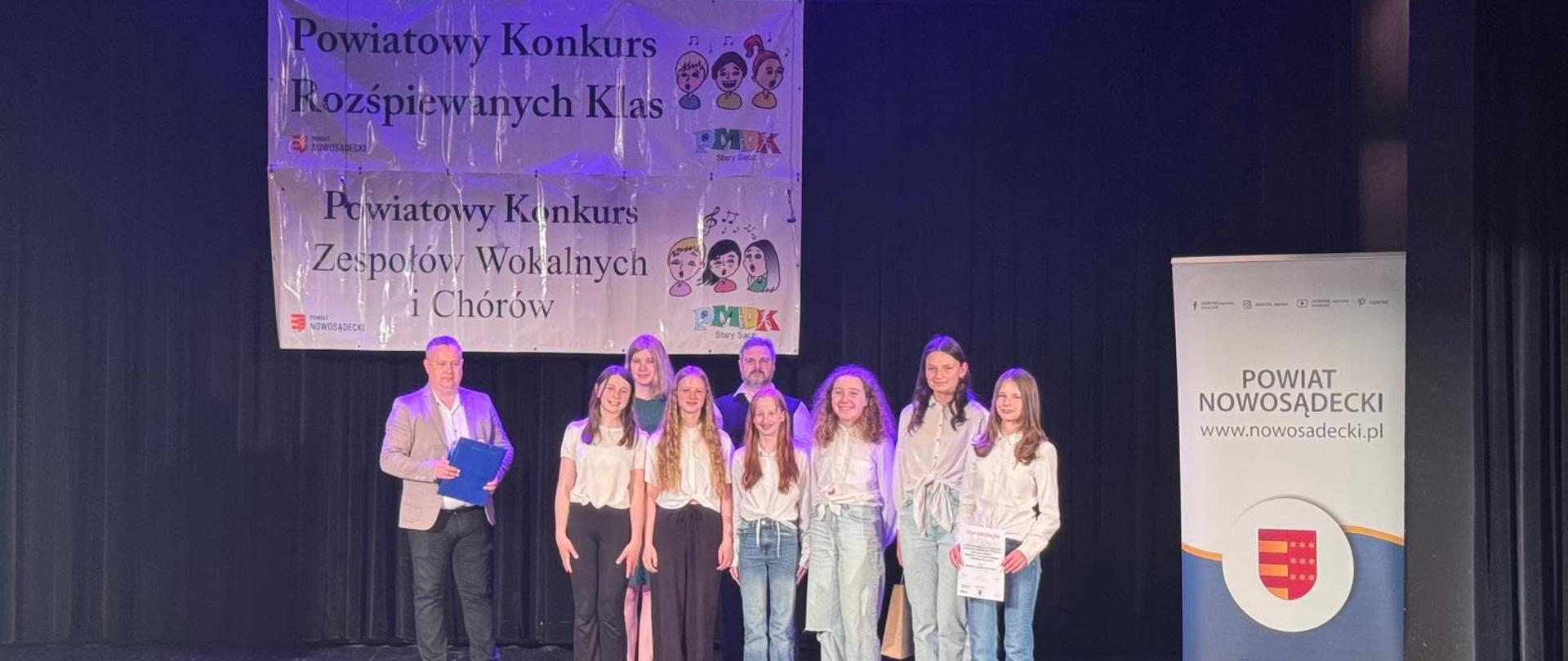 Wyróżnione w konkursie dziewczynki odbierają dyplom i gratulacje na scenie