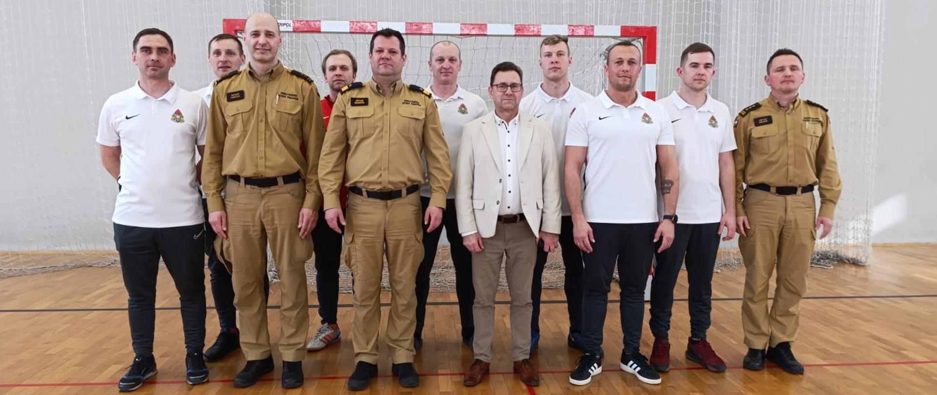 Zdjęcie grupowe w hali sportowej na tle jednej z bramek