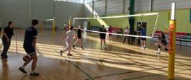 Grupa młodzieży grająca w siatkówkę na hali sportowej podczas ferii. 