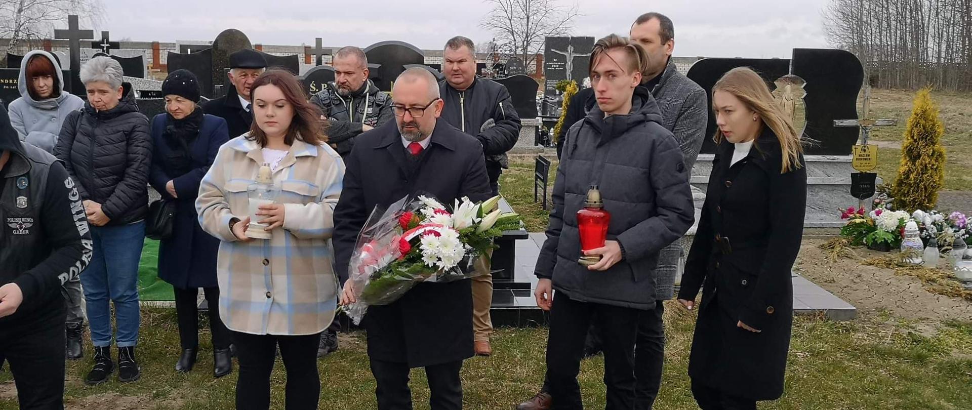 Starosta Przasnyski Krzysztof Bieńkowski złożył kwiaty na grobie śp. por. Pawła Krajewskiego w 12. rocznicę katastrofy smoleńskiej. Na zdjęciu Starosta Krzysztof Bieńkowski trzymający wieniec, dookoła przedstawiciele Młodzieżowej Rady Powiatu oraz rodzina zmarłego porucznika Pawła Krajewskiego.