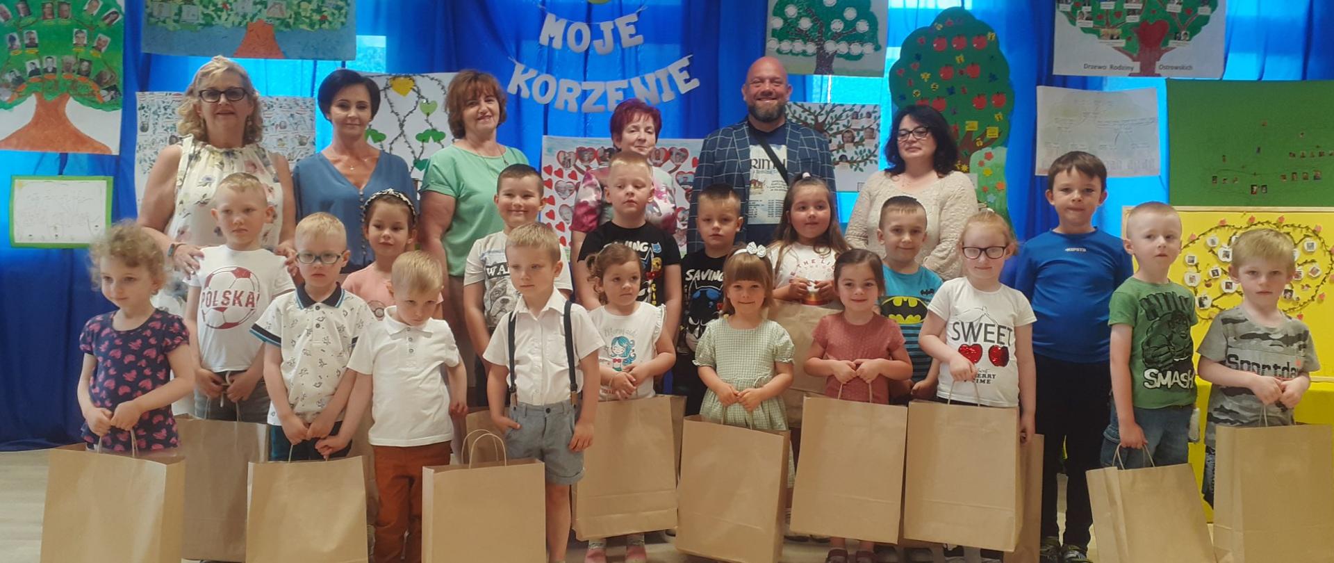 Dzieci z nagrodami, nauczyciele na tle napisu Moje korzenie