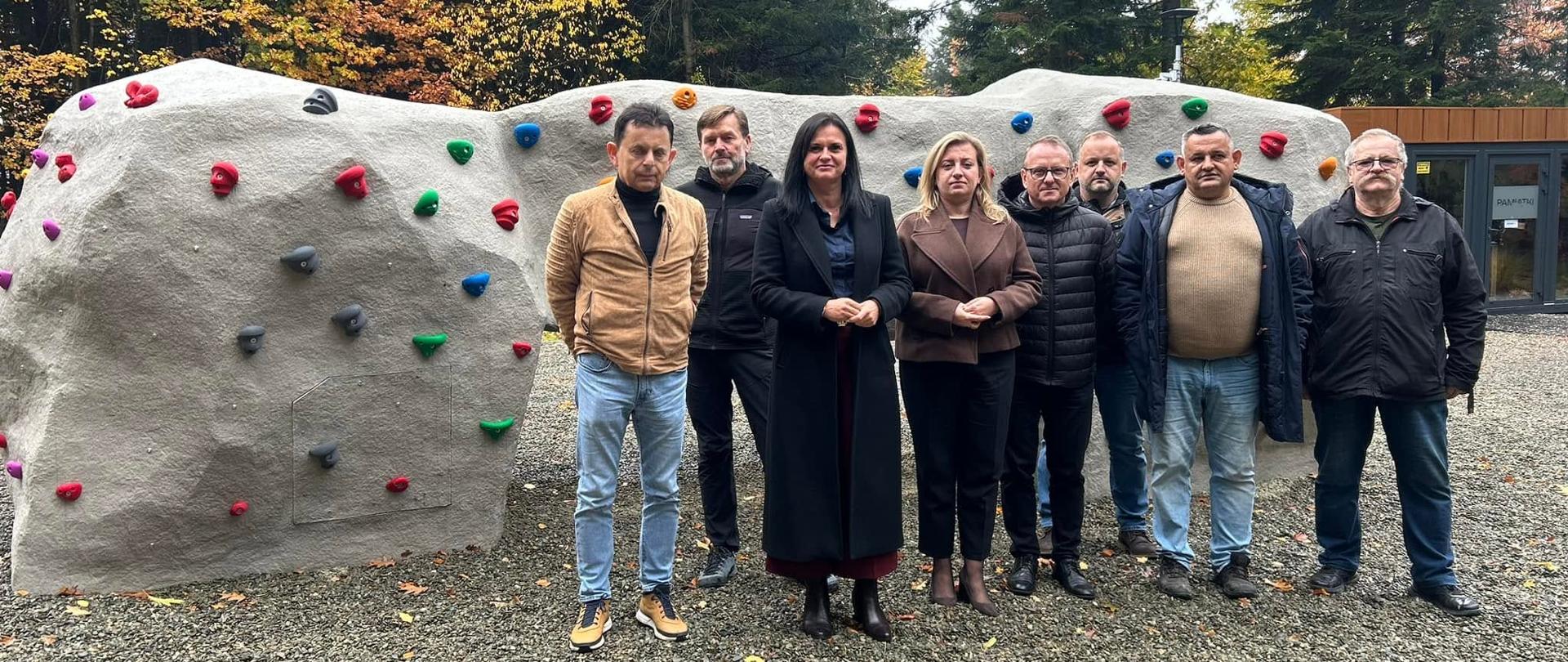 Osoby stojące przed ścianką wspinaczkową
