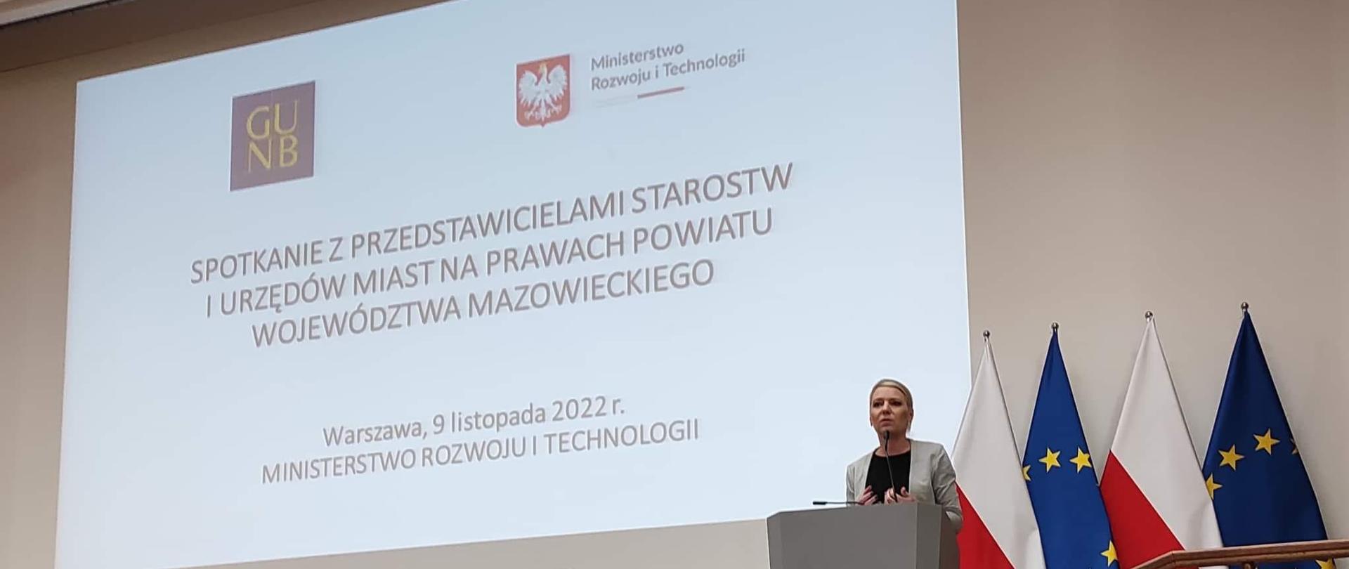 Zdjęcie przedstawia prelegentów z Ministerstwa Rozwoju i Technologii stojących i siedzących na scenie.