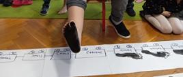 Dzieci w trakcie zabawy - malowanie stóp, które są odbijane na kartkach