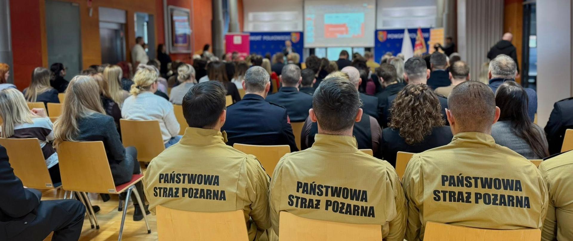 Osoby siedzą na widowni tyłem