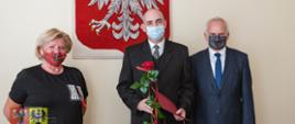 trzy osoby na tle godła