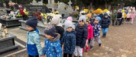 Grupa dzieci na cmentarzu w nawiązaniu do Święta Zmarłych