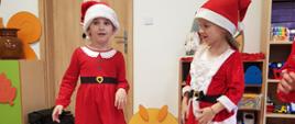 Dwoje dzieci w czapkach świętego Mikołaja stoi w sali zabaw