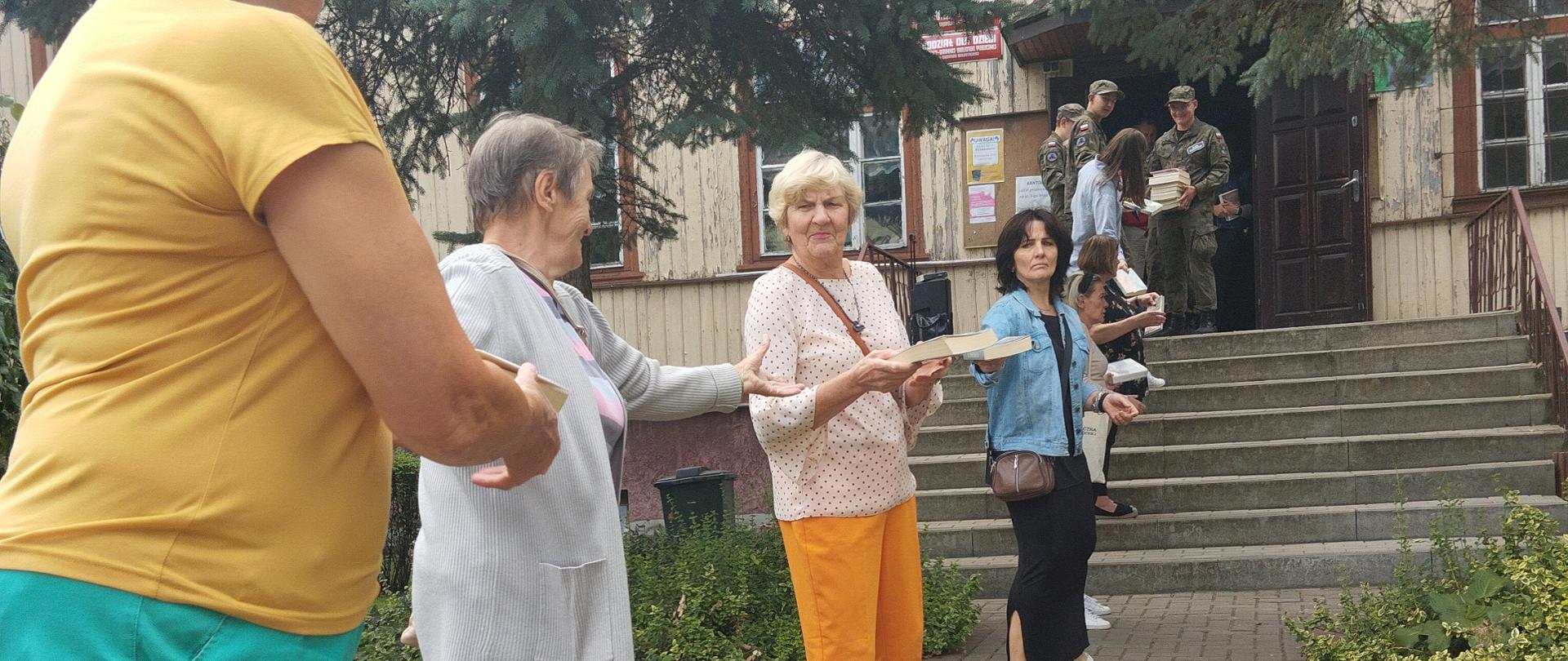 Ludzie przekazujący sobie książki z rąk do rąk