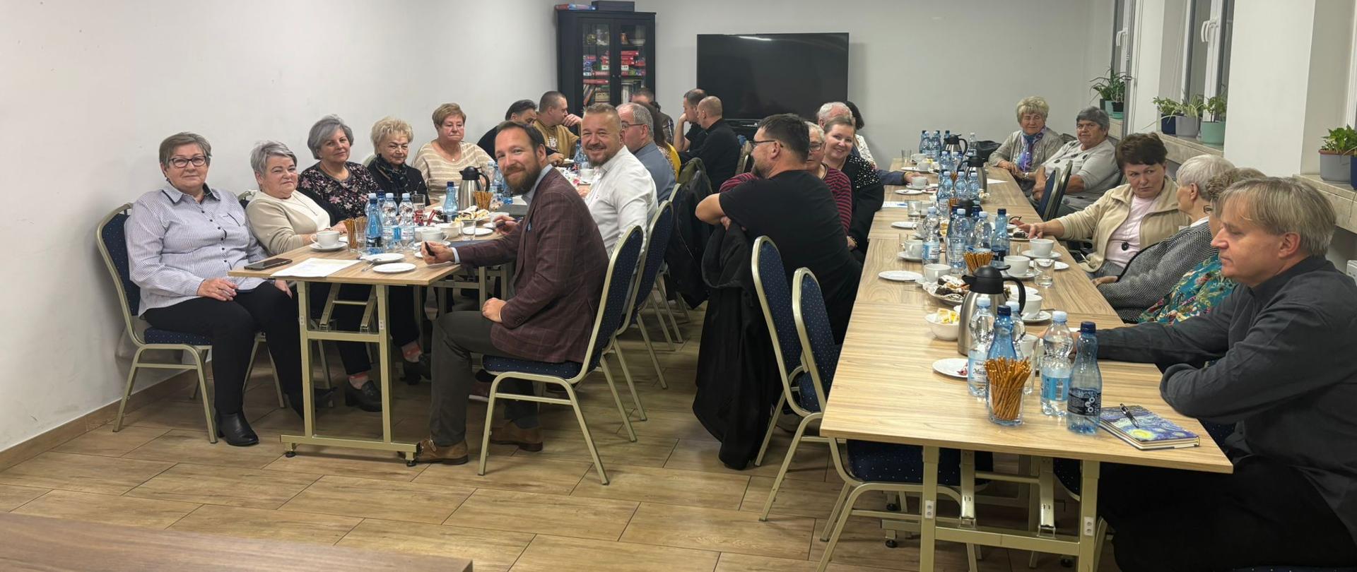 Ludzie siedzący przy stołach w jasnym pomieszczeniu