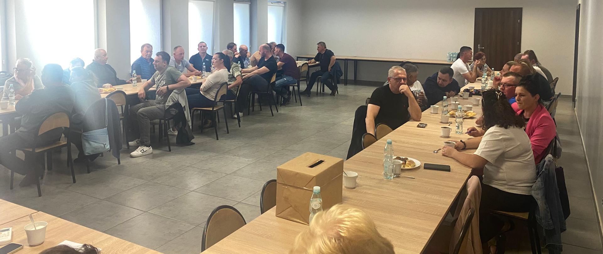 ludzie siedzący przy stołach ustawionych w kształcie litery U na nowoczesnej sali konferencyjnej